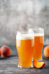 Boozy Refresing Cold Hard Peach Cider or Craft Fruit Beer in a Pint Glass on wooden table. Copy space