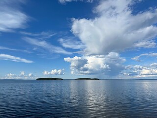 View of a tranquil lake with islands beneath a blue, partly cloudy sky in Sweden.