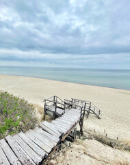 A beautiful scenic beach view featuring a relaxing wooden pathway along a cloudy sky