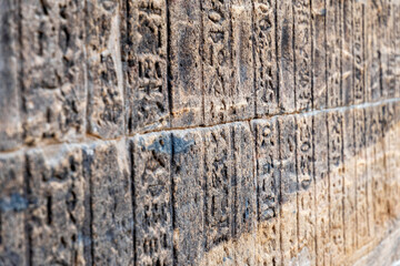 Close-up shot of weathered stone blocks covered in ancient Egyptian hieroglyphs. Intricate carvings...