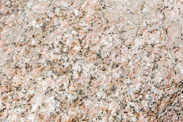 Natural texture and pattern of a pink granite rock surface, with its composition of varied mineral...