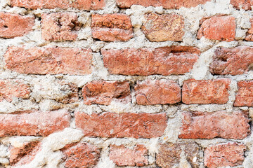 Old brick wall with weathered red bricks and thick, crumbling mortar. Texture is rich with details, highlighting the age of the construction