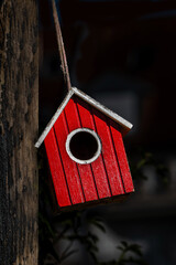 Rotes Vogelhaus an einem braunen Pfosten im Garten