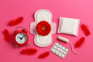 Feminine hygiene composition with menstrual pad tampon red flower pain relief pills and alarm clock on pink background symbolizing period care timing and health awareness