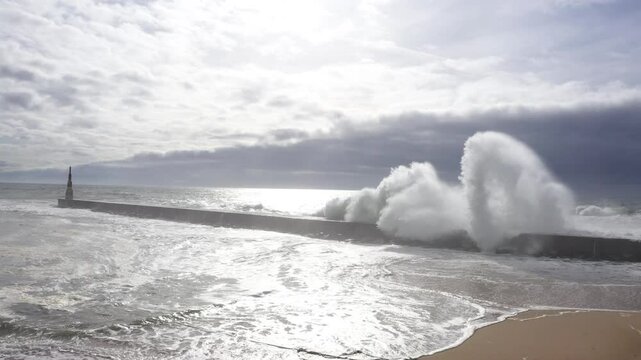 Huge waves crashing over Breakwater during winter storm Atlantic waves washing the lighthouse on Praia da Aguda sandy beach at Aguda settlement near Porto, Portugal. Incredible 4K flying drone video.