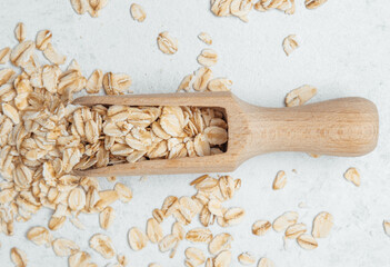 Oats in a wooden scoop scattered on a light surface