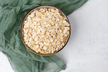 Oats in a bowl on a textured surface with green fabric nearby