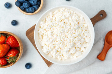 Fresh cottage cheese with strawberries and blueberries on a wooden board