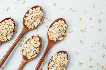 Wooden spoons filled with oats arranged on a light background