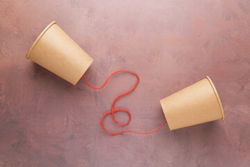Old style brown cup phone with red string, toy phone, two-way communication concept