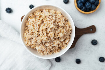 Delicious oatmeal served in a bowl with fresh blueberries on a wooden surface