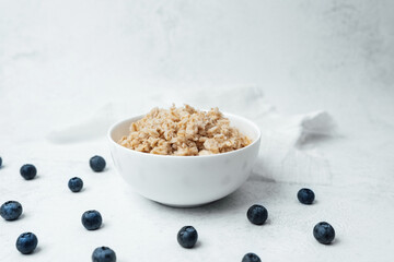 Healthy oatmeal bowl with blueberries on a light background