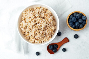 Breakfast bowl of oatmeal with fresh blueberries on a light background