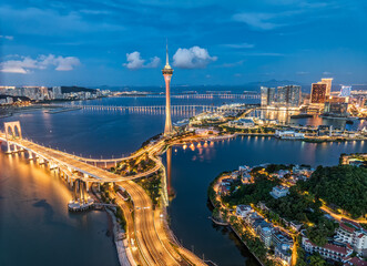 Illuminated cityscape with building and connecting bridges over the water at night in Macau.