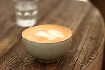 Coffee in a nice ceramic cup and glass of water on the table. Selective focus.