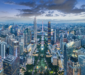Fototapeta premium Panoramic view of the illuminated modern city financial district skyline with tall towers at dusk in Guangzhou, China.