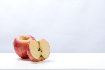 Whole red apple and half-cut apple with seeds on clean white surface and bright background, showing juicy texture, fresh flesh, and natural color of ripe healthy fruit