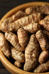 Tumeric rhizomes in bowl on table, closeup