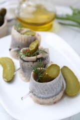 Delicious herring rolls with pickles and dill on table, closeup