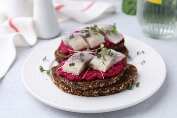 Tasty sandwiches with herring and horseradish sauce on light table, closeup