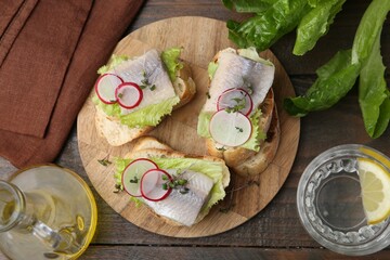 Tasty sandwiches with herring served on wooden table, flat lay