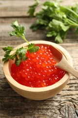 Red caviar and parsley on wooden table, closeup