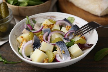 Delicious salad with herring, vegetables and mustard in bowl on wooden table, closeup