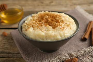 Delicious rice pudding with cinnamon, honey and almonds on wooden table, closeup