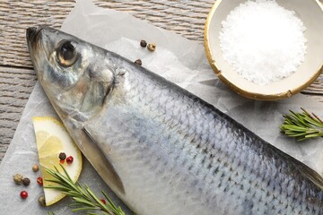 Salted herring and spices on wooden table, flat lay