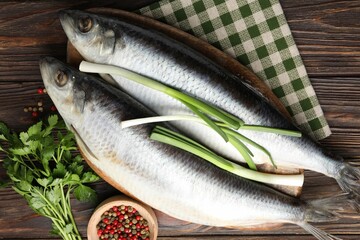Salted herrings and spices on wooden table, flat lay
