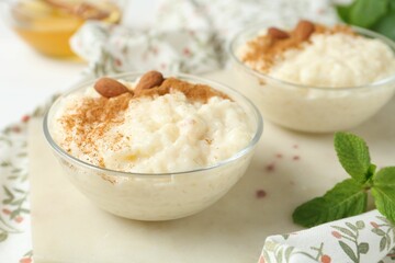 Delicious rice pudding with cinnamon, almonds and mint on table, closeup