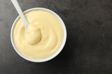 Tasty vanilla pudding with spoon on black table, top view. Space for text