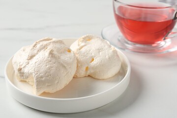 Delicious homemade meringue cookies and tea on light table, closeup
