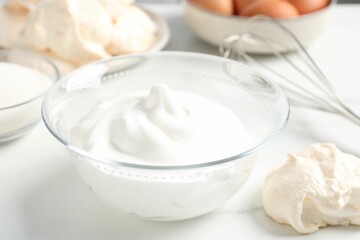 Delicious homemade meringue cookies and whipped cream on light table, closeup