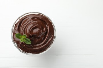 Delicious chocolate pudding with mint on white wooden table, top view. Space for text