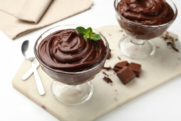 Delicious chocolate pudding in dessert bowls on white table, closeup