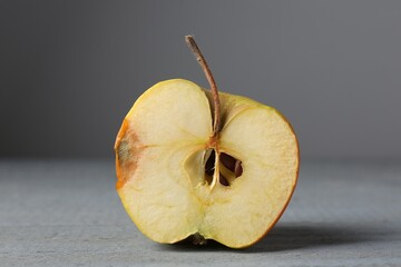 Half of overripe apple on grey wooden table, closeup