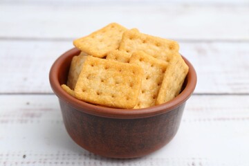 Tasty salty crackers on white wooden table, closeup