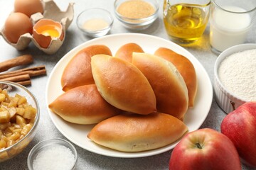 Tasty baked patties and ingredients on light grey table, closeup