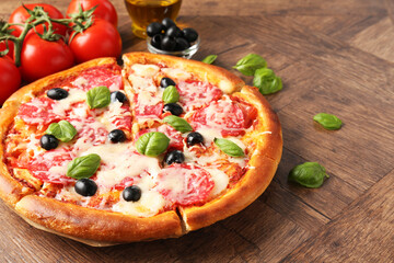 Tasty pizza and ingredients on wooden table, closeup. Space for text