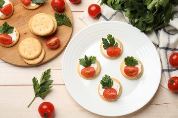 Tasty crackers with cream cheese, tomatoes and parsley on white wooden table, flat lay