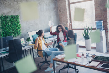 Group of young professionals collaborating and celebrating success in a modern office space with diverse teamwork and creative interactions