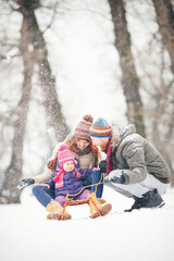 Young family with baby girl outdoors playing in the snow