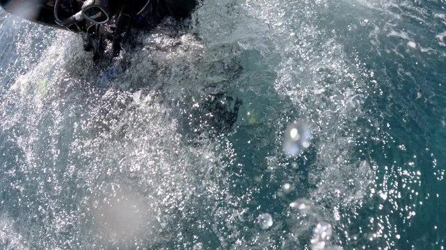 Diver performing backward roll entry and signaling success in the ocean