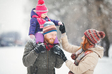 Young family with baby girl having fun in the snow
