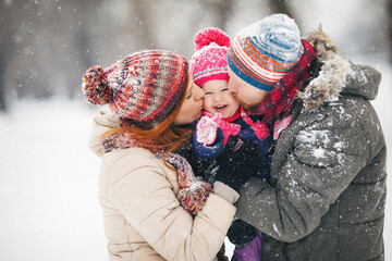 Young family with baby girl outdoors playing in the snow