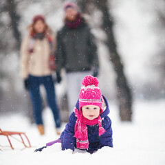 Young family with baby girl outdoors having fun in the snow. Shallow DOF. Developed from RAW; retouched with special care and attention; Small amount of grain added for best final impression.