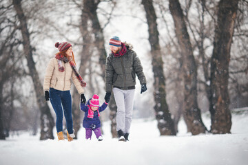 Young family with baby girl outdoors having fun in the snow. Shallow DOF. Developed from RAW; retouched with special care and attention; Small amount of grain added for best final impression.