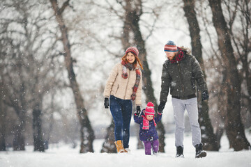 Young family with baby girl having fun in the snow