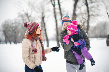 Young family with baby girl outdoors having fun in the snow. Shallow DOF. Developed from RAW;...